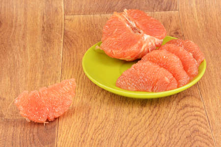 Ripe grapefruit in a green plate on a wooden backgroundの写真素材