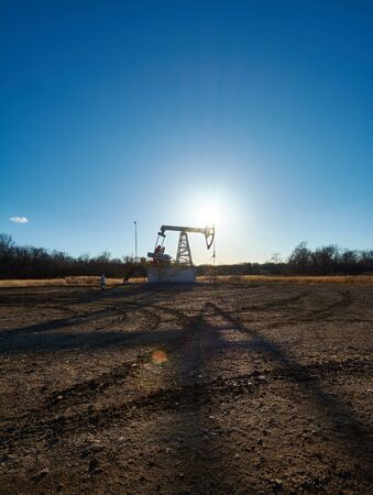 Oil rig in the field at sunsetの写真素材