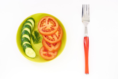 Cucumber and tomato in green plate white backgroundの写真素材
