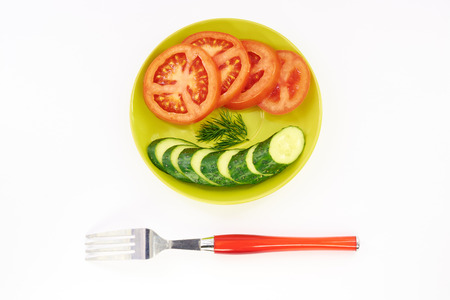 Cucumber and tomato in green plate white backgroundの写真素材