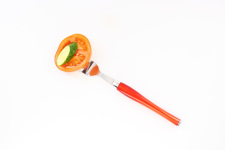Cucumber and tomato on fork white backgroundの写真素材