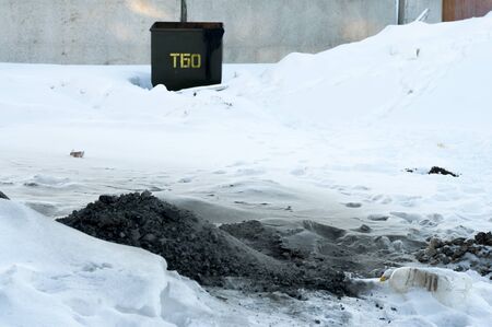 Ashes thrown into the snow next to a container for wasteの写真素材