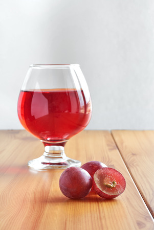 Red wine in a glass on a wooden table and grapesの写真素材
