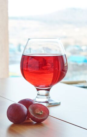 Red wine in a glass on a wooden table and grapesの写真素材