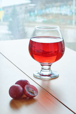 Red wine in a glass on a wooden table and grapesの写真素材