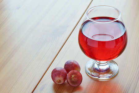 Red wine in a glass on a wooden table and grapesの写真素材