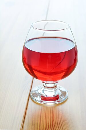 Red wine in a glass on a wooden tableの写真素材
