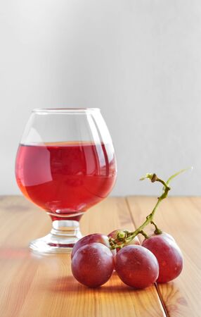 Red wine in a glass on a wooden table and grapesの写真素材