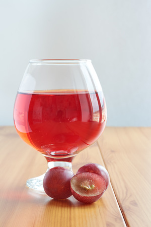 Red wine in a glass on a wooden table and grapesの写真素材