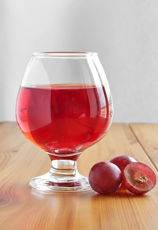 Red wine in a glass on a wooden table and grapesの写真素材