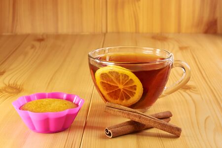 Black tea with lemon and cinnamon cupcake on a wooden tableの写真素材