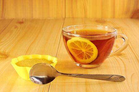 Black tea with lemon and cinnamon cupcake on a wooden tableの写真素材