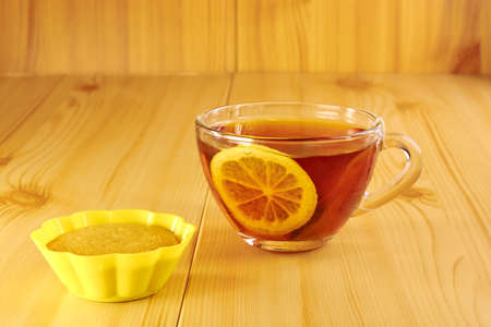 Black tea with lemon and cinnamon cupcake on a wooden tableの写真素材
