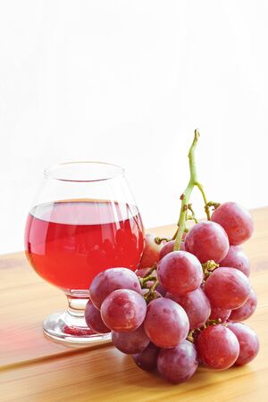 Red wine in a glass on a wooden table and grapesの写真素材