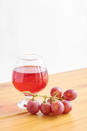 Red wine in a glass on a wooden table and grapesの写真素材