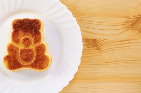Cinnamon cake in the shape of a bear cub on a wooden table
