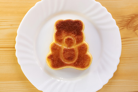 Cinnamon cake in the shape of a bear cub on a wooden tableの写真素材