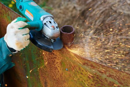 Angle grinder cuts rusty metal plate sparks ventの写真素材
