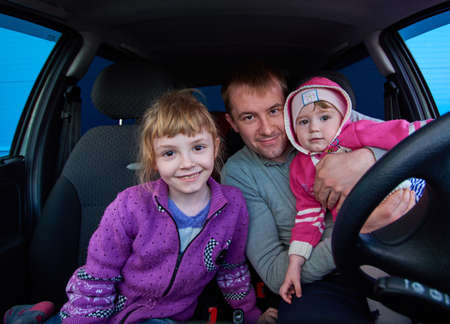 A man with two daughters sitting in the car