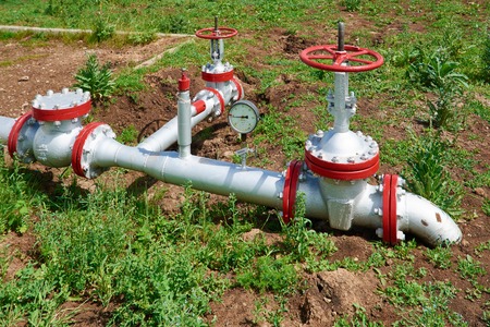 Valves on the pipeline at the mouth of the oil wells in the meadow on a summer day