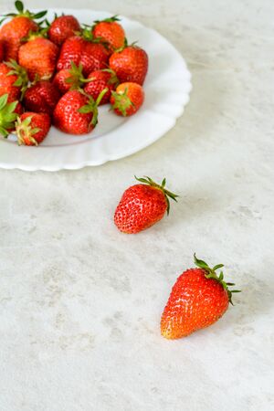 Strawberries on a white plate on the tableの写真素材