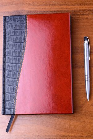 Notebook and pen on the wooden tableの写真素材