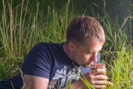 Man lying on the grass and enjoying the smell of strawberriesの写真素材