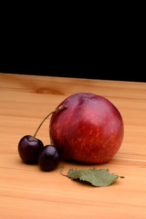Nectarines and cherries on a wooden table on a black backgroundの写真素材