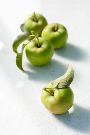 Green unripe apples with a leaf on a white backgroundの写真素材