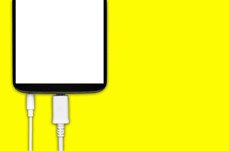 Smartphone with cable and micro usb 3.5 jack on a yellow backgroundの写真素材