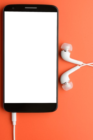 Smartphone with connected headphones on an orange backgroundの写真素材