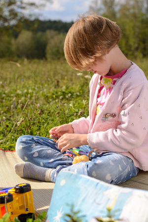 Girl playing with dolls in the meadow in summerの写真素材
