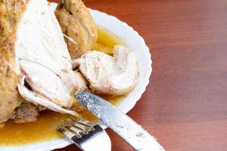 Baked chicken on a white plate with a fork and knifeの写真素材