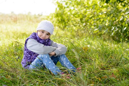 Child sitting on the grass in early fallの写真素材