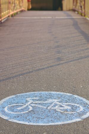 Blue road sign bicycle track on the asphalt at sunsetの写真素材