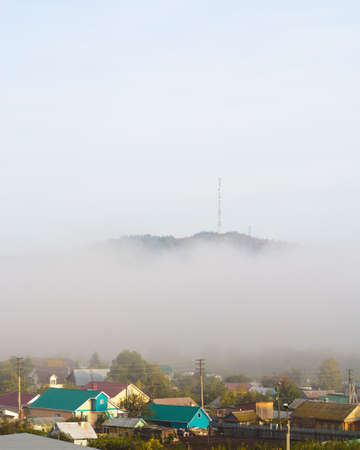 View of the village under the hill in the fog at dawnの写真素材