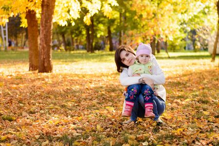 Mother with a baby hugging in the autumn parkの写真素材