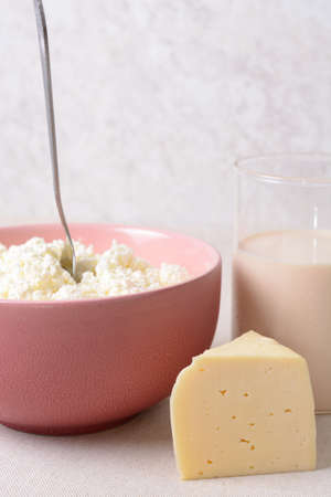 Air cottage cheese with spoon in a deep plate, a piece of cheese and a glass of warm milk