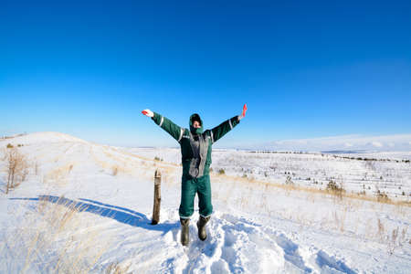 Young man jumping on top of a hill in the winterの写真素材