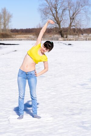 Girl doing exercises outdoors in winter on snowの写真素材