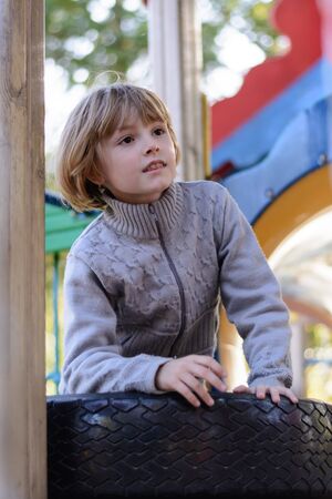 Little girl playing on the playground in autumn dayの写真素材