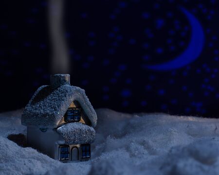 Toy house standing in the snow of cotton moonlit nightの写真素材
