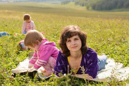 Mother and two daughters sitting at a picnic on the grassの写真素材