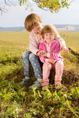 The sisters sitting on the grass on a summer dayの写真素材