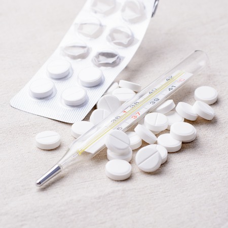 Thermometer and pills scattered on a napkinの写真素材