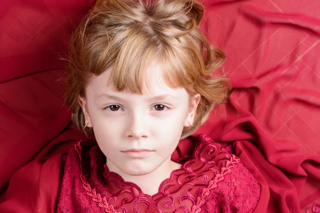 Beautiful girl in a red dress lying on the floorの写真素材