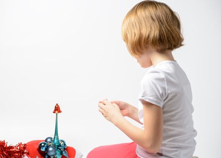 Girl playing with Christmas decorations on a white backgroundの写真素材