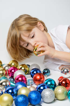 Girl playing with Christmas decorations on a white backgroundの写真素材
