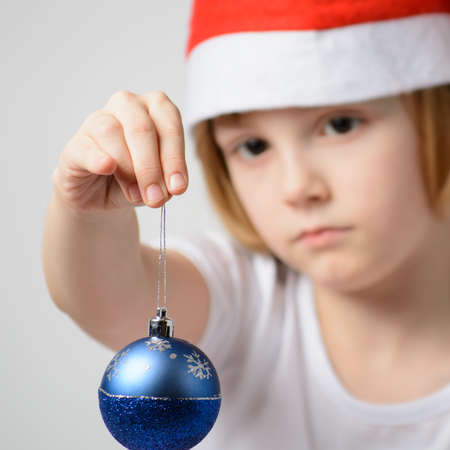 Girl in santa hat holding a Christmas ballの写真素材