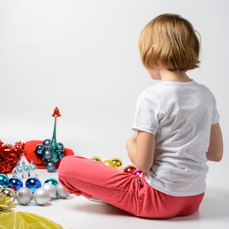 Girl playing with Christmas decorations on a white backgroundの写真素材